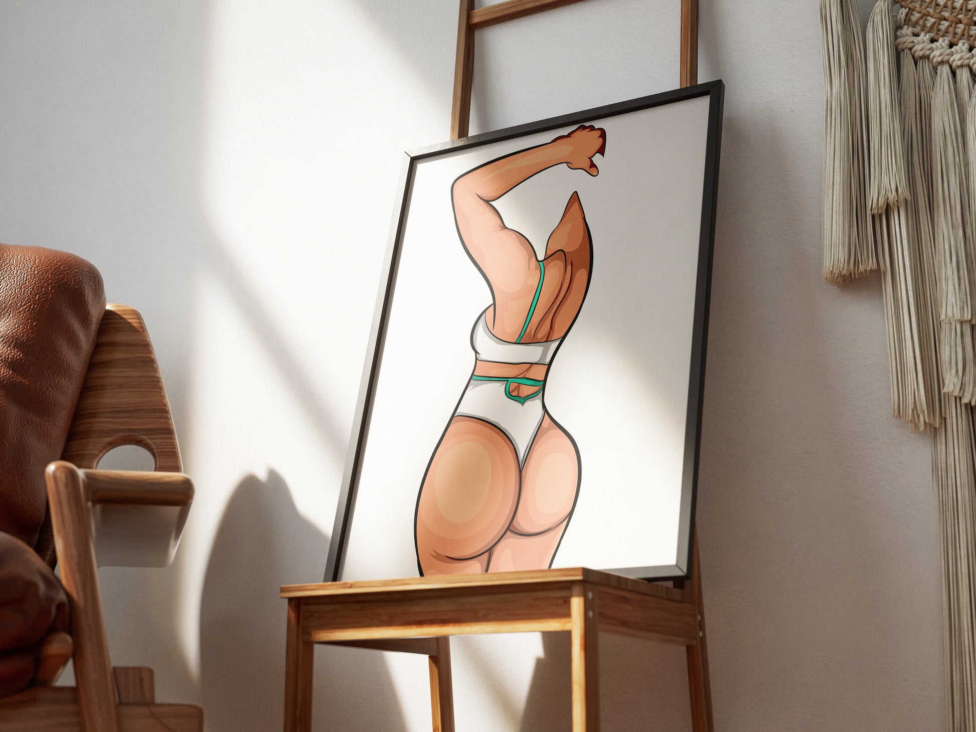 Digital artwork of Bikini Model 59, featuring bold lines and expressive details, framed and displayed on a wooden chair.