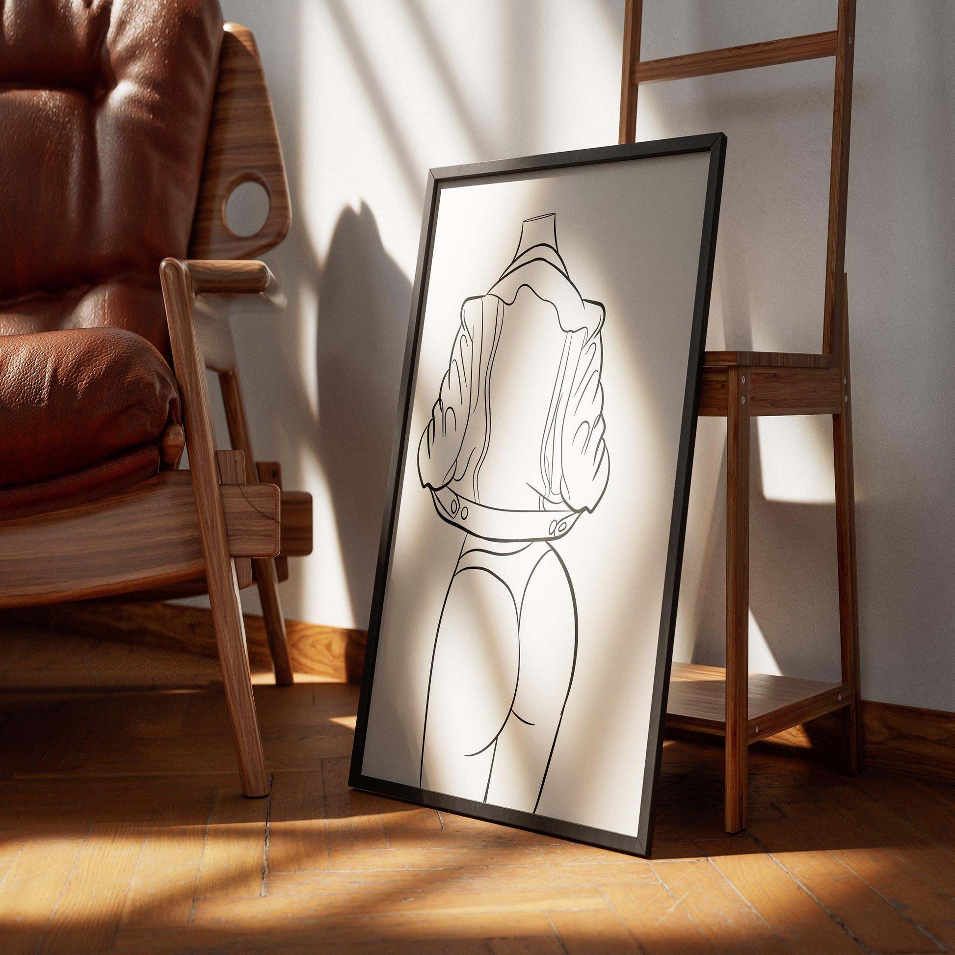Digital art print of Lingerie Model 33 in line art style, displayed in a wooden frame on the floor, featuring bold curves and clean lines.